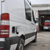 O dubă albă cu rezervorul deschis în apropierea unei autospeciale roșii