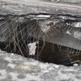 O imagine de prim-plan a unei gropi masive și a unei surpări adânci în carosabilul de asfalt