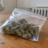 O pungă din plastic cu canabis pe o masă de lemn