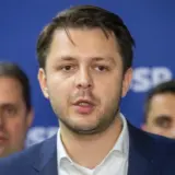 Un portret de tip plan mediu al viceprimarului Ruben Lațcău, vorbind în fața unui panou albastru