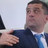 Un portret de aproape al lui Ștefan-Ovidiu Popa, purtând un costum bleumarin, cămașă albă și cravată albastră, uitându-se în sus și spre dreapta