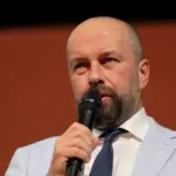 A man speaking into a microphone in front of an Astra Film Festival 33 branded backdrop