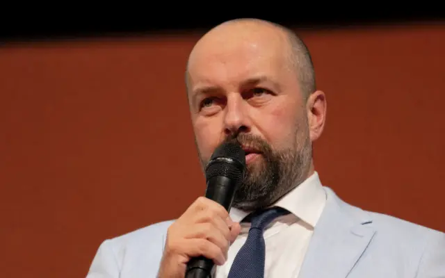 A man speaking into a microphone in front of an Astra Film Festival 33 branded backdrop