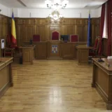 Interiorul unei săli de judecată cu steagul României în fundal