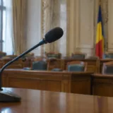 Microfon și steagul României într-o sală oficială pentru audieri parlamentare