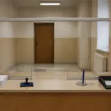 Un ghișeu administrativ cu geam de protecție, văzut din perspectiva funcționarului