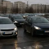 O imagine cu o aglomerare de autoturisme care stau la coadă pe o șosea cu linii de tramvai, într-o zonă urbană cu blocuri în fundal
