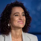 Portrait of the Romanian Minister of Culture, Raluca Turcan, smiling against a blurred blue background